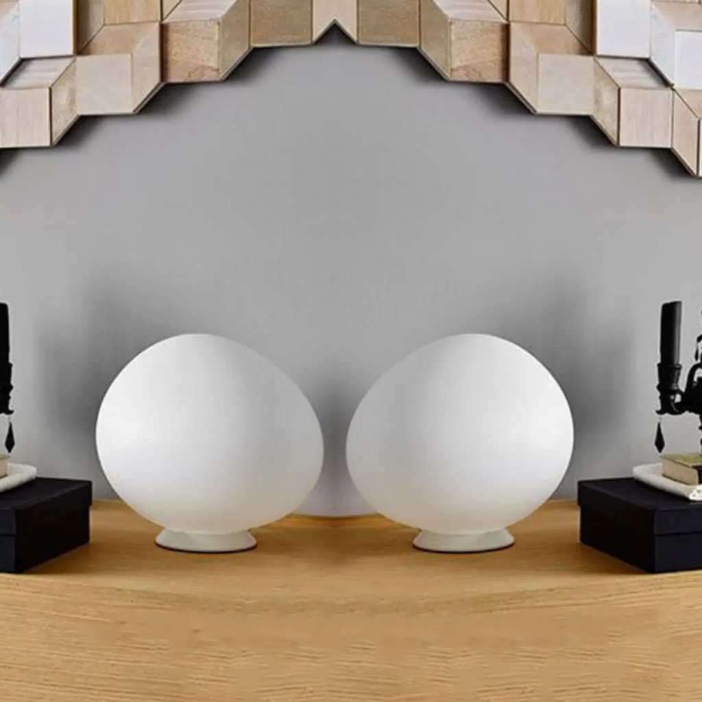 Gregg Table Lamp shown as two frosted oval glass lamps on a wooden table, emitting a soft organic glow in a minimalist setting