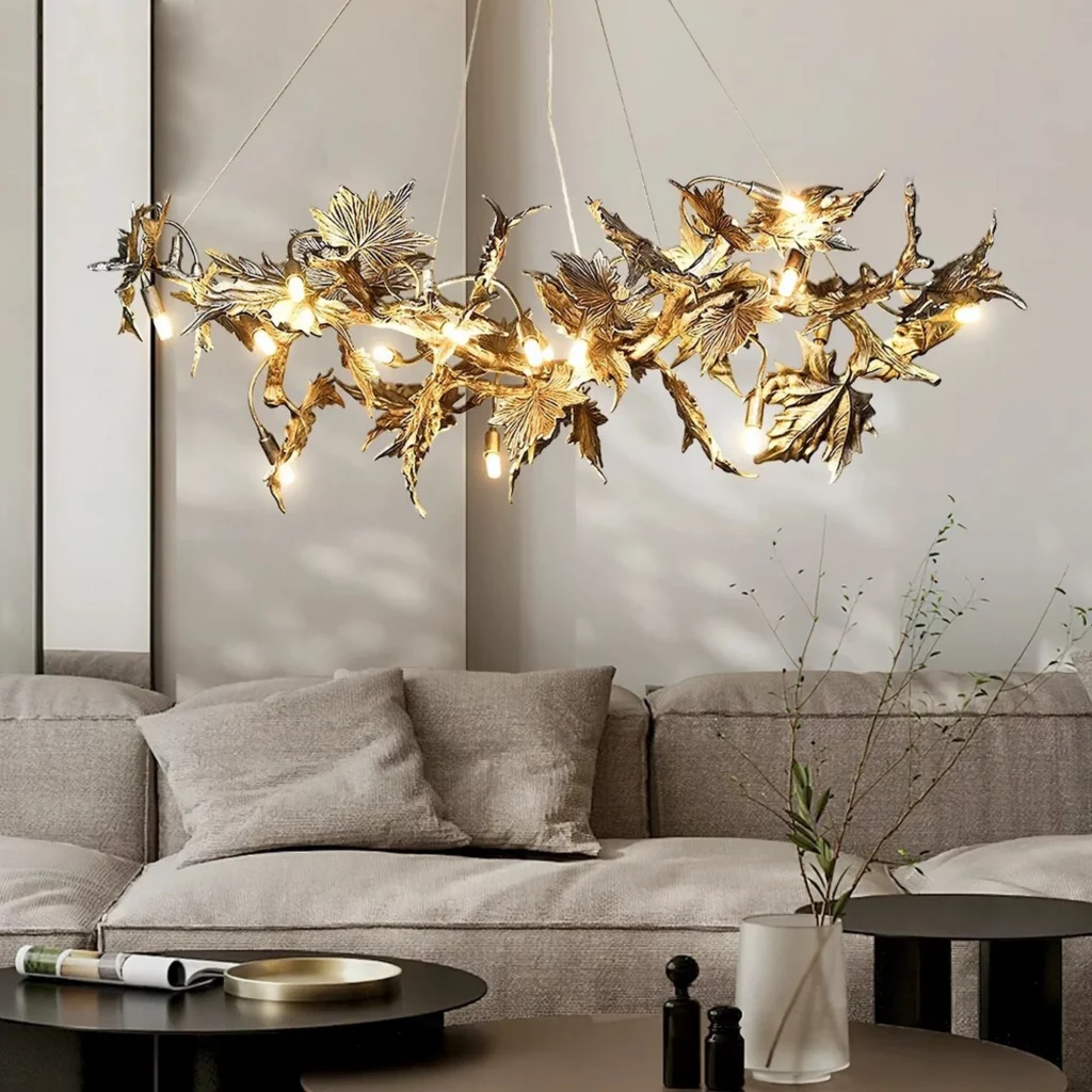 Intricate Laurel Blossom Organic Chandelier with golden leaf-like metal branches and small glowing bulbs over a neutral sofa.