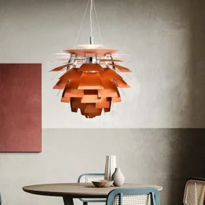 The iconic copper Artichoke PH Chandelier is suspended over a round wooden table with woven chairs in a modern room with gray and burnt orange walls.