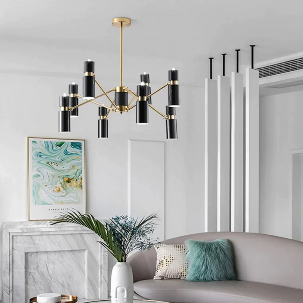 Modern living room with marble fireplace and soft seating, highlighted by a Nordic Design Black Branch chandelier with gold accents and sleek cylindrical lights.