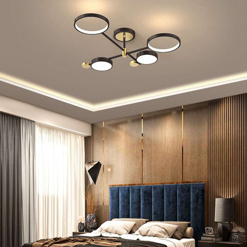 Modern Ring Design Black Gold LED Chandelier with four circular lights on a black frame, illuminating a luxury bedroom with blue headboard.