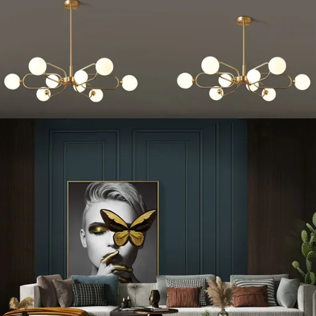 Multi Head Copper Arm Chandelier with globe bulbs in a modern living room featuring teal paneled walls, plush sofa, and bold butterfly portrait art