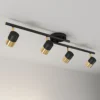 Modern surface-mounted track light with four rotatable cylindrical heads in a sophisticated black and gold finish.