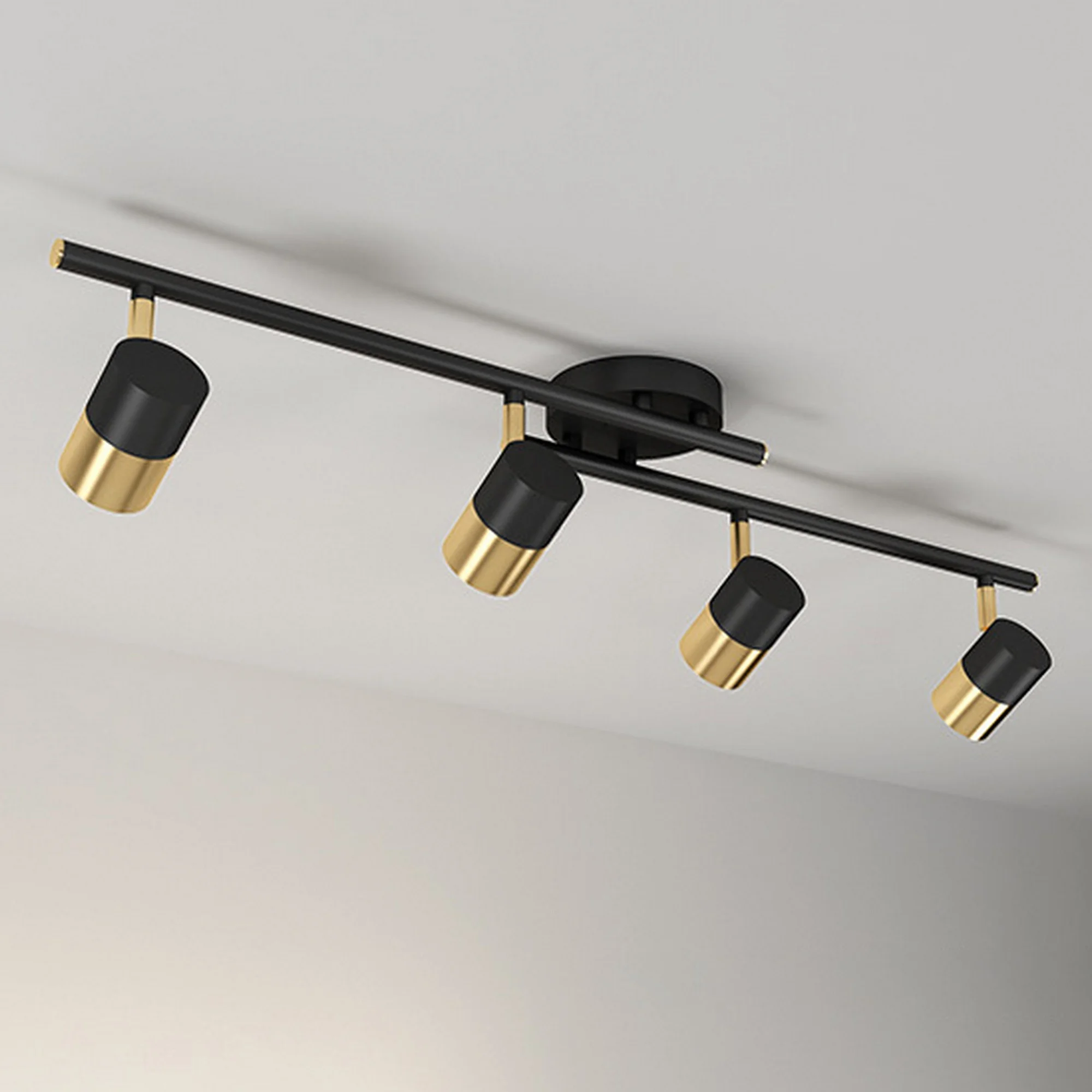 Modern surface-mounted track light with four rotatable cylindrical heads in a sophisticated black and gold finish.