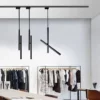 Modern retail space with minimalist black pendant lights featuring unique intersecting vertical and angled tube spotlights.