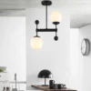 Minimalist kitchen interior featuring a Minimalist Frosted Glass Chandelier with black metal arms and soft glowing globes above a clean workspace.