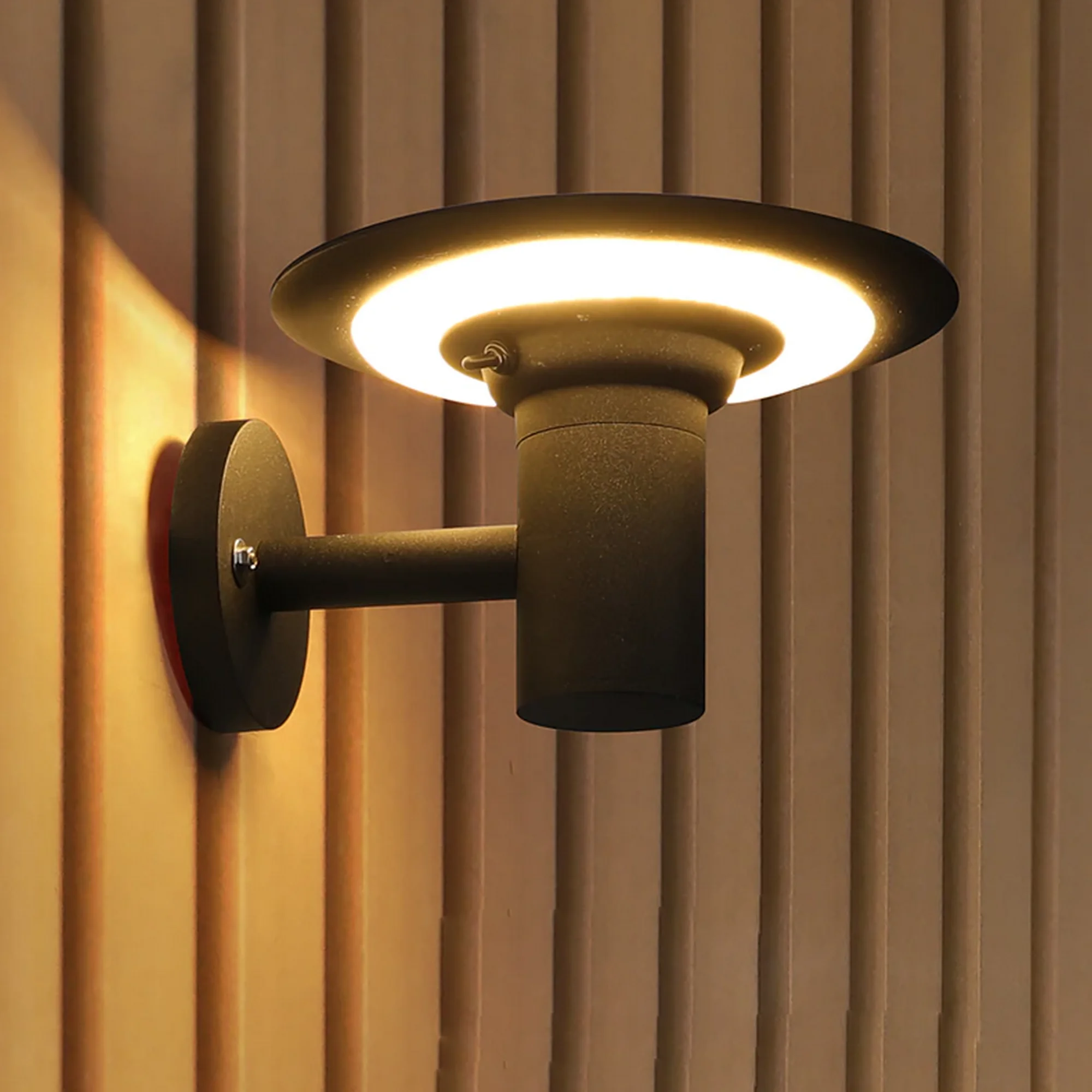 5-61463 UFO Shaped LED Outdoor Wall Light: A black, saucer-style wall lamp casting a warm circular glow against a slatted wood texture.