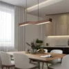 Camur LED Linear Suspension—curved wooden pendant light above dining table, modern kitchen lighting with warm white glow.