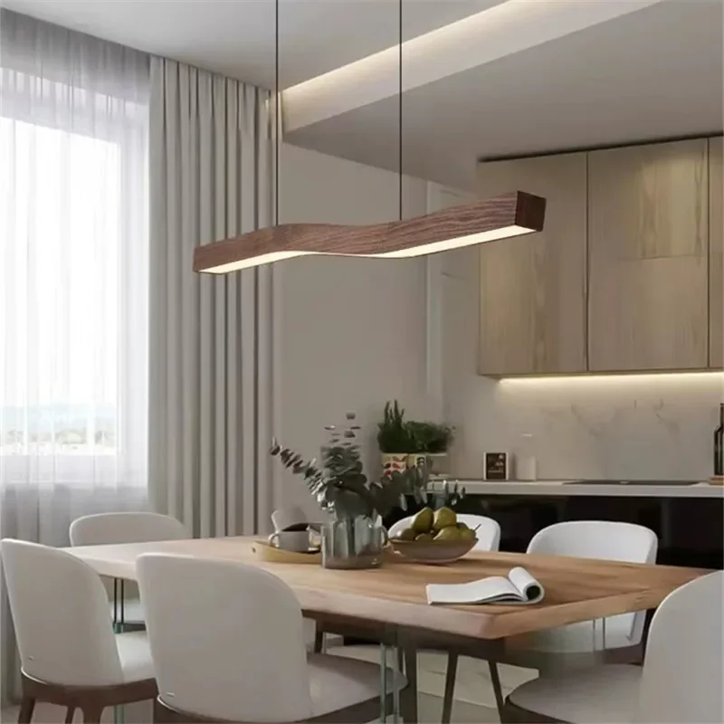 Camur LED Linear Suspension—curved wooden pendant light above dining table, modern kitchen lighting with warm white glow.