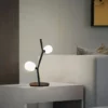 Ivy Table Lamp with a minimalist design featuring two spherical lights on a black, branch-like structure, placed on a modern side table.