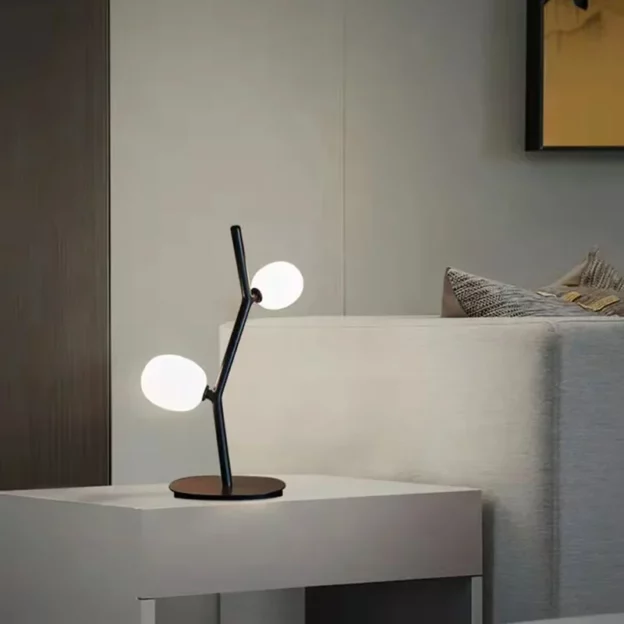Ivy Table Lamp with a minimalist design featuring two spherical lights on a black, branch-like structure, placed on a modern side table.