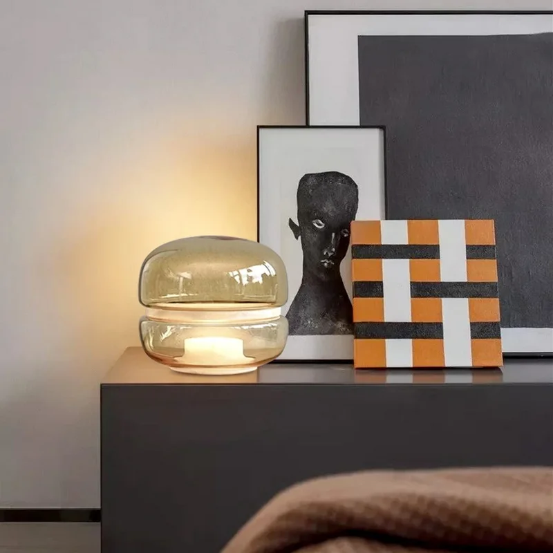 Macaron Table Lamp with a stylish, stacked glass design, placed on a sleek side table alongside abstract art and a minimalist portrait.