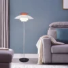 The PH 80 Floor Lamp stands beside a sofa, casting warm light in a cozy living room with a stylish design.