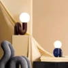 The Adalyn Table Lamp features sculptural, curved bases in brown and blue with round white globes on top, set against a soft backdrop.