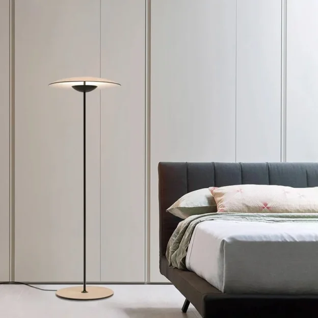 A sleek GINGER Floor Lamp stands beside a modern bed, adding soft lighting to the minimalist bedroom.