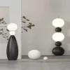 The Tama Lampa Floor Lamp features stacked spheres and a sleek design, illuminating a modern living space.