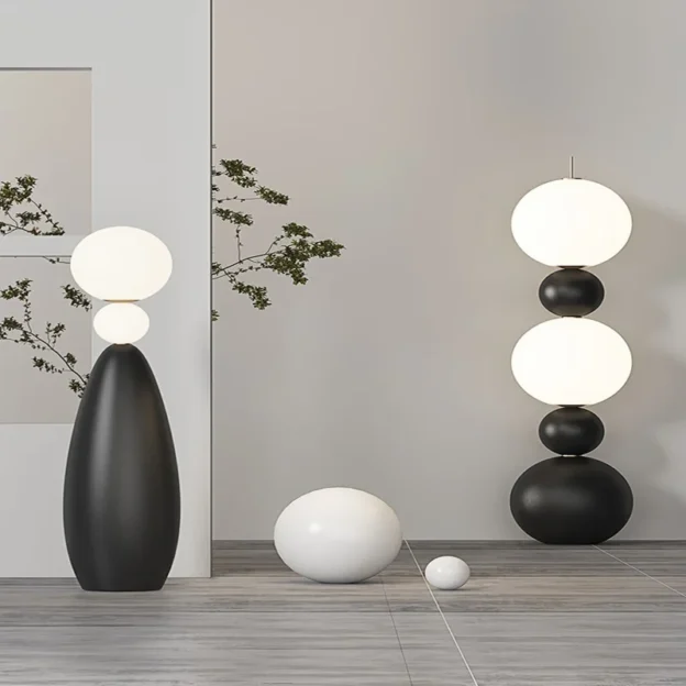 The Tama Lampa Floor Lamp features stacked spheres and a sleek design, illuminating a modern living space.
