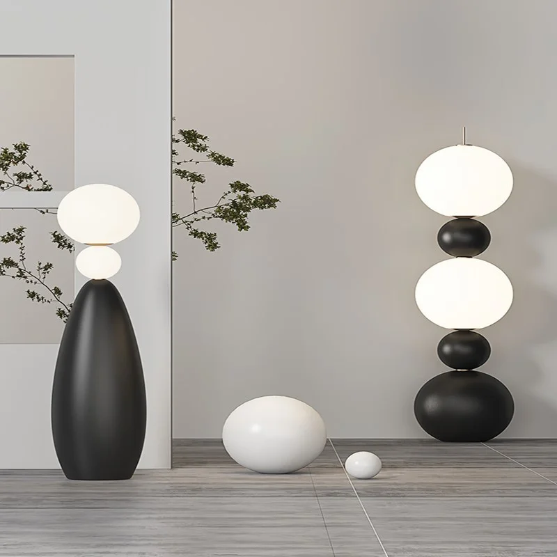 The Tama Lampa Floor Lamp features stacked spheres and a sleek design, illuminating a modern living space.